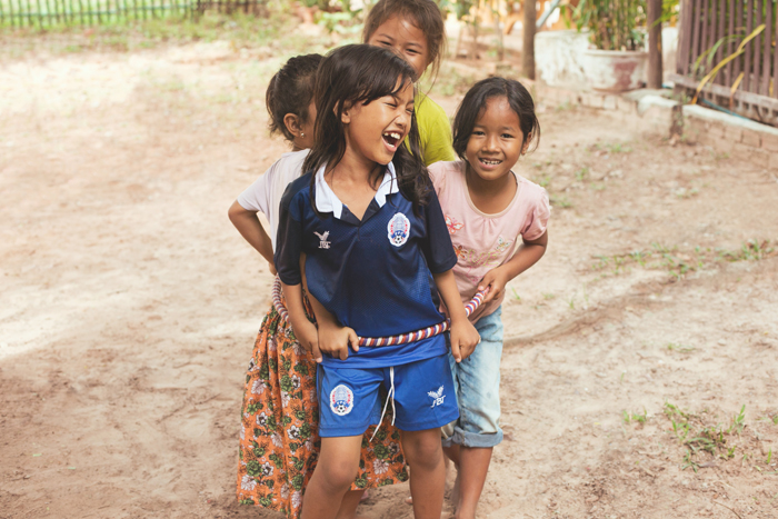 Smejúce sa deti v na školskom dvore. Kambodža na motorke Honda Win. 